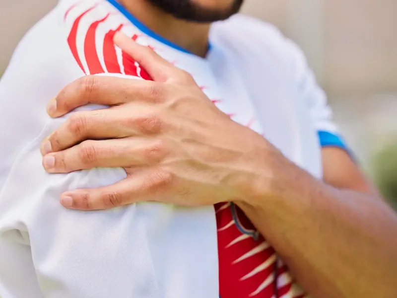Person holding their shoulder in discomfort