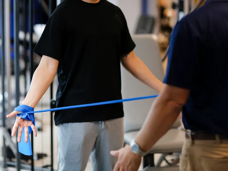 Patient training with a resistance band while a therapist guides the movement