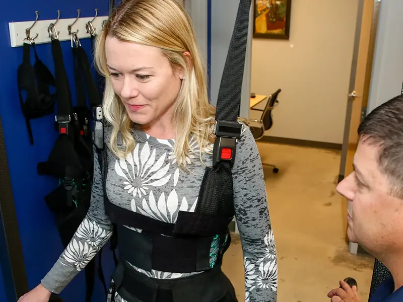 Patient walking in a body-weight support harness with a therapist assisting