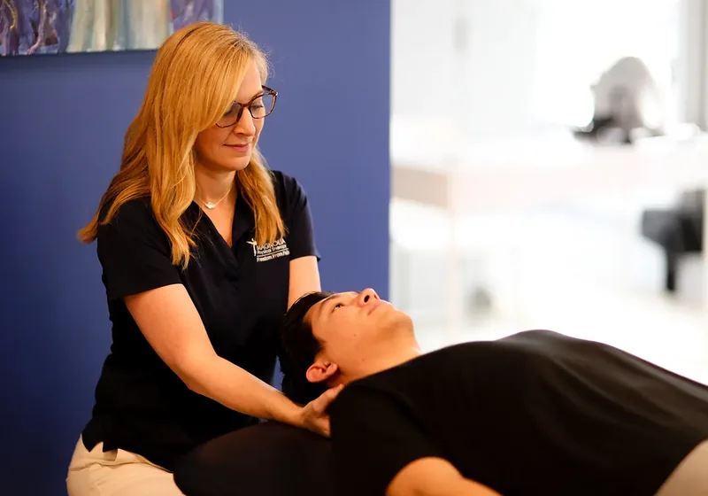 A licensed physical therapist treating a patient&rsquo;s shoulder while the patient lies on a treatment table