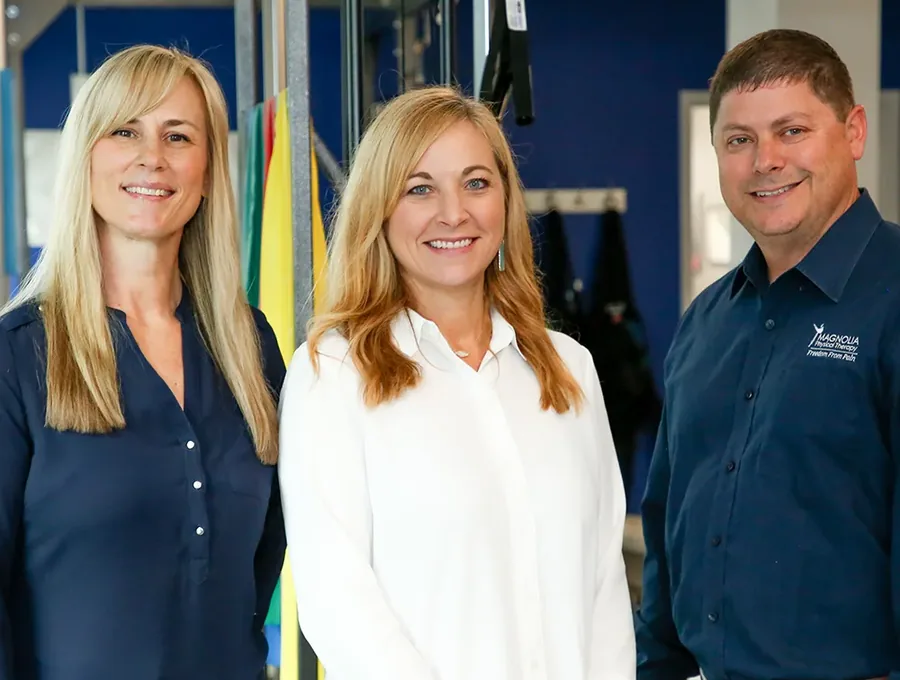 Three Magnolia Physical Therapy therapists standing together in the clinic gym